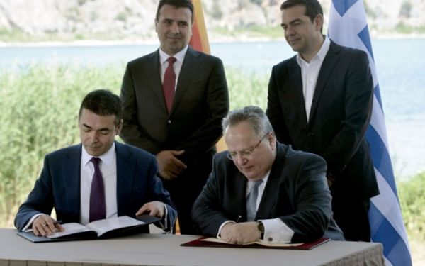 Министр иностранных дел Македонии Никола Димитров (слева) и его греческий коллега Никос Котзиас (справа) подписывают соглашение о переименовании бывшей югославской республики.
