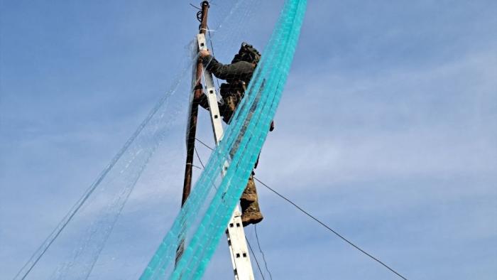 работы по установке противодроровых сетей для защиты дорог. Ко всем опасностям добавляется ещё и работа на высоте. На фото боец инженерно-сапёрного отряда имени генерала Карбышева в составе Добровольческого Корпуса